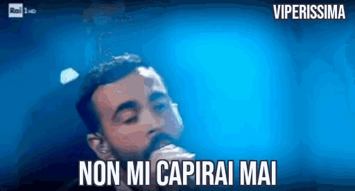 a man with a beard is singing into a microphone with the words non mi capirai mai written below him