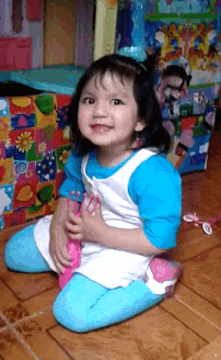 a little girl is sitting on the floor holding a microphone