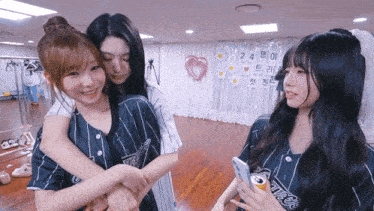 three girls hugging in front of a sign that says 24 on it
