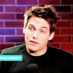 a young man wearing a black shirt with a sayberry sticker