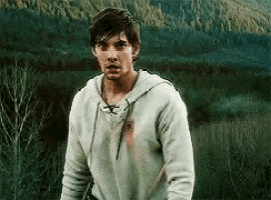 a man in a white hoodie is standing in front of a mountain .
