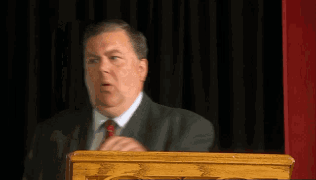 a man in a suit and tie is standing behind a podium