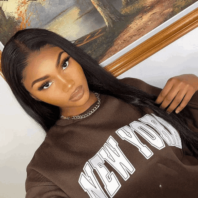 a woman wearing a brown sweatshirt that says new york on it