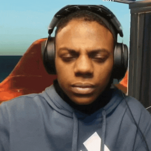 a man wearing headphones and sunglasses looks at the camera with his eyes closed