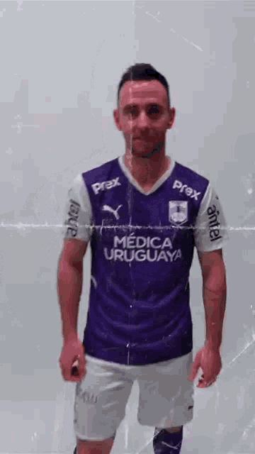 a man wearing a purple jersey that says medica uruguay