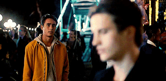 a man in a yellow jacket is standing in a crowd of people .