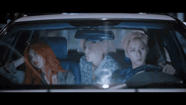 a man and two women are sitting in a car looking out the window