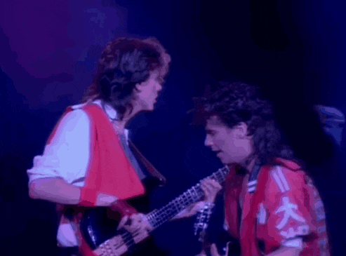 two men are playing guitars on a stage in front of a purple background .