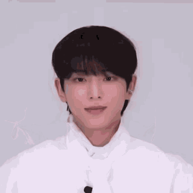 a young man wearing a white shirt and tie is making a heart shape with his hands .
