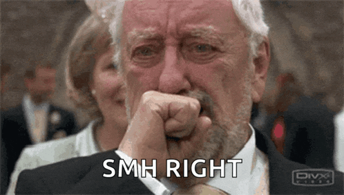 an older man in a suit is crying and covering his mouth with his fist .