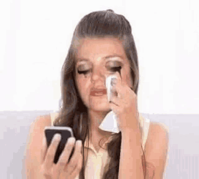 a woman is crying while holding a cell phone .