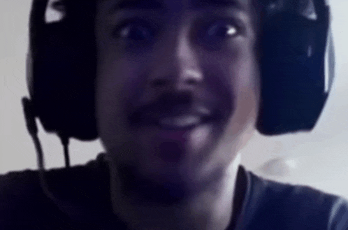 a man wearing headphones and a microphone is making a funny face .