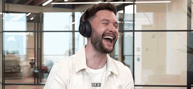 a man wearing headphones is laughing and saying " yes "