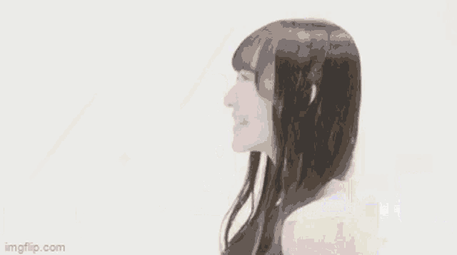 a woman with long black hair is smiling and looking to the side .
