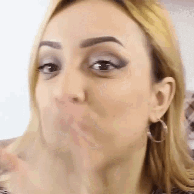 a woman wearing hoop earrings is making a funny face with her mouth open .