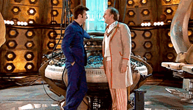 two men are standing next to each other in a room talking