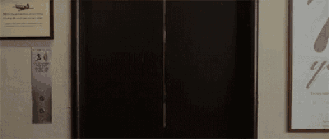 a black elevator is sitting in a room next to a wall with a picture on it .