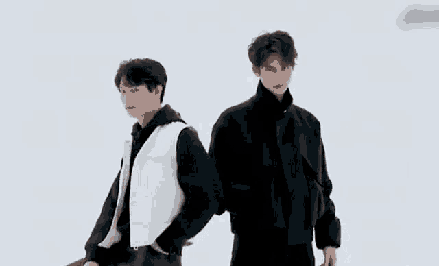 two young men are standing back to back in a black and white photo .