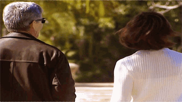a man in a brown jacket and a woman in a white sweater are walking together