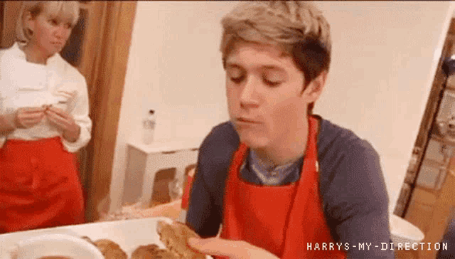 a man wearing an apron is eating a piece of food while a woman watches