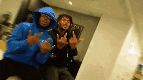 two men are posing for a picture and one of them is wearing a blue hoodie