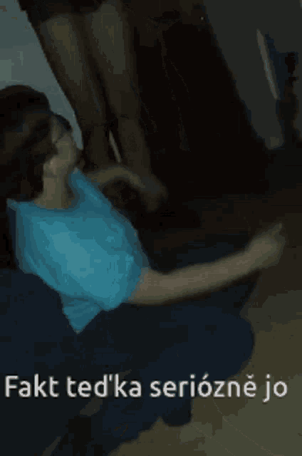 a man in a blue shirt is sitting on the floor drinking from a bottle