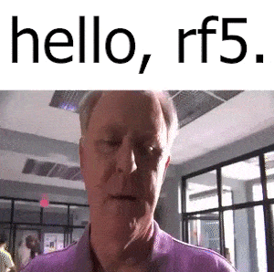 a man in a purple shirt is standing in a hallway and says hello , rf5 .