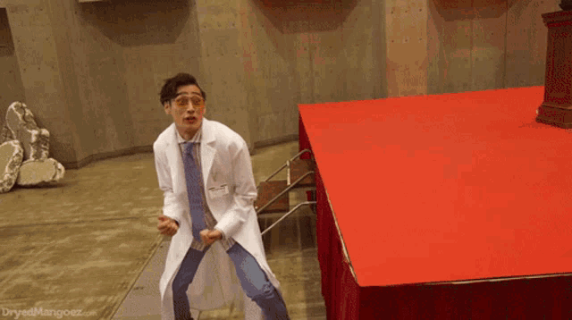 a man in a lab coat giving the middle finger with a dryedmangoez.com logo in the corner