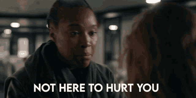 a woman talking to another woman with the words " not here to hurt you " behind her