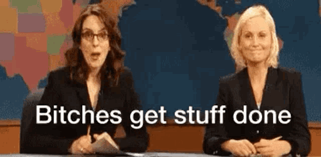 two women are sitting at a desk with the words `` bitches get stuff done '' written on the bottom .
