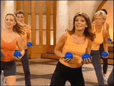 a group of women are holding blue dumbbells in a gym