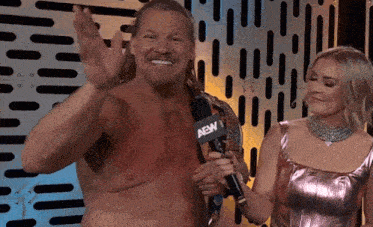 a man without a shirt is holding a microphone while standing next to a woman .