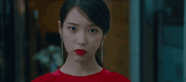 a close up of a woman in a red dress with red lipstick .