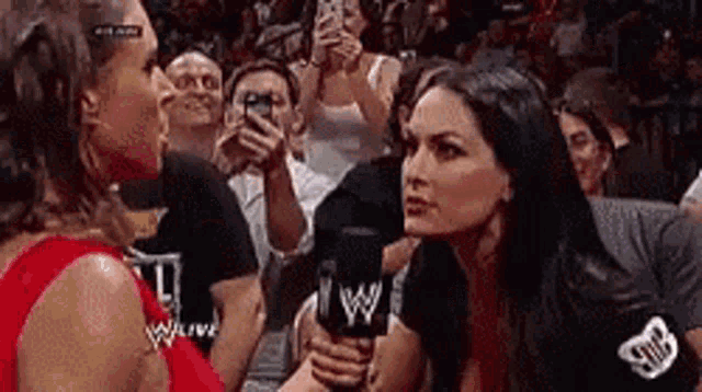 two women are talking to each other in front of a crowd .