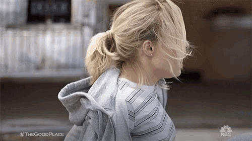 a woman with her hair in a ponytail is wearing a striped shirt and a gray hoodie .