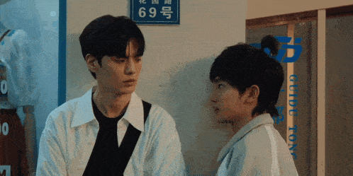 two young men are standing next to each other in front of a sign that has the number 69 on it