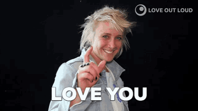 a woman wearing a denim jacket is smiling and saying `` love you '' .