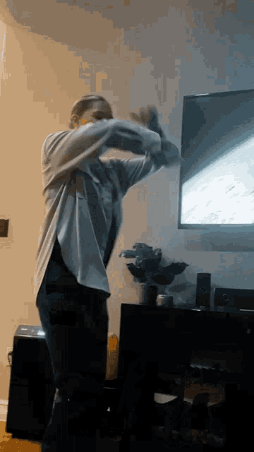 a woman is dancing in front of a flat screen tv in a living room .