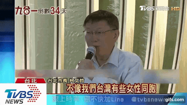a man is holding a microphone in front of a tvbs news sign