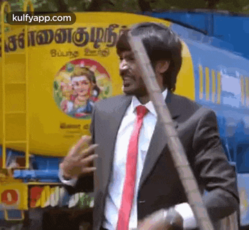 a man in a suit and tie is standing in front of a truck holding a stick .