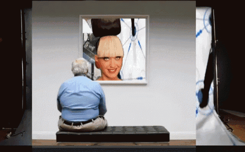 a man is sitting on a bench looking at a painting of a woman