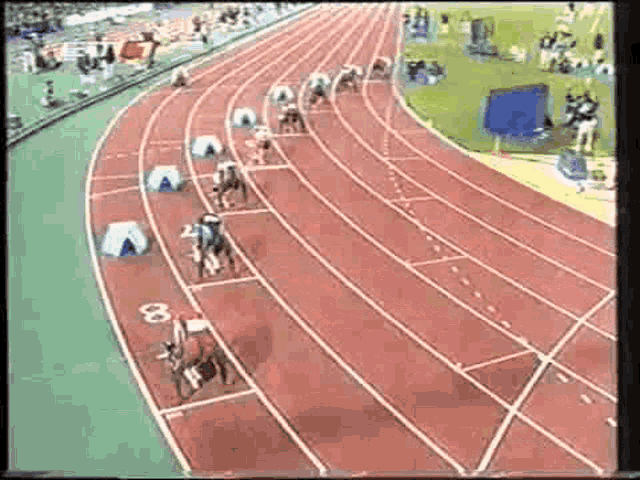 a group of people are racing on a track with the number 8 on the starting line