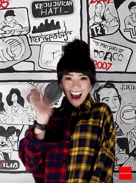 a woman wearing a plaid shirt is standing in front of a wall with drawings of people and the year 2007