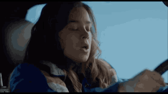 a woman is sitting in the back seat of a car with her eyes closed and her mouth open .