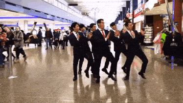 a group of men in suits and ties are dancing together in an airport