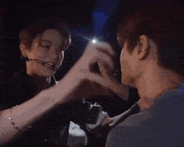two men are making a heart shape with their hands while standing next to each other .