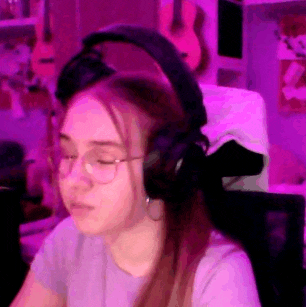 a girl wearing headphones and glasses is sitting in a chair .