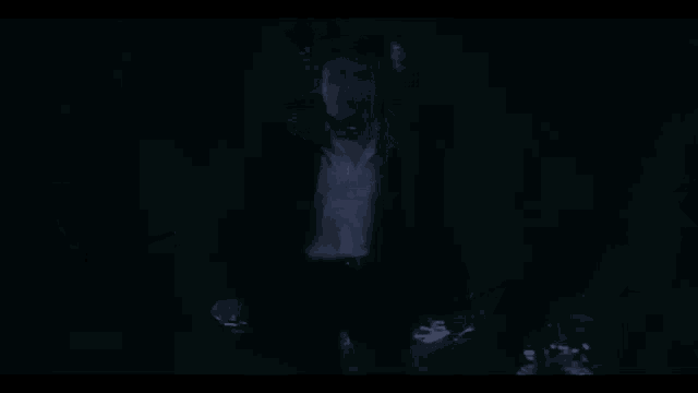a man in a white shirt is standing in a dark room