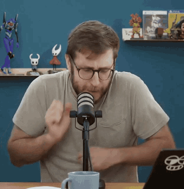a man wearing glasses is sitting in front of a microphone and a laptop