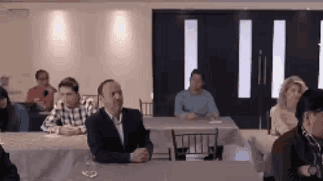 a group of people are sitting at tables in a room